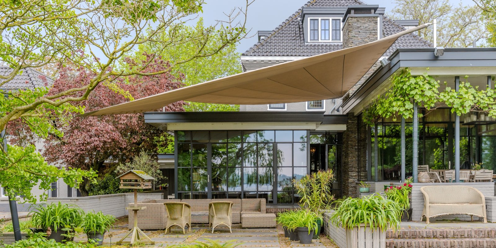 Een zonnezeil van ShadowArt boven het terras van een woning